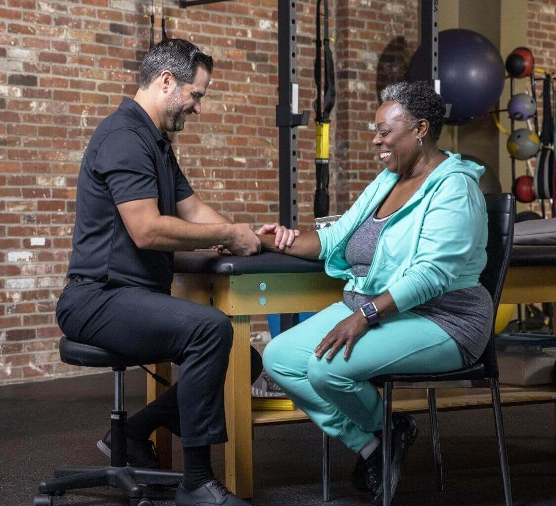 Male physical therapist with woman patient holding arm
