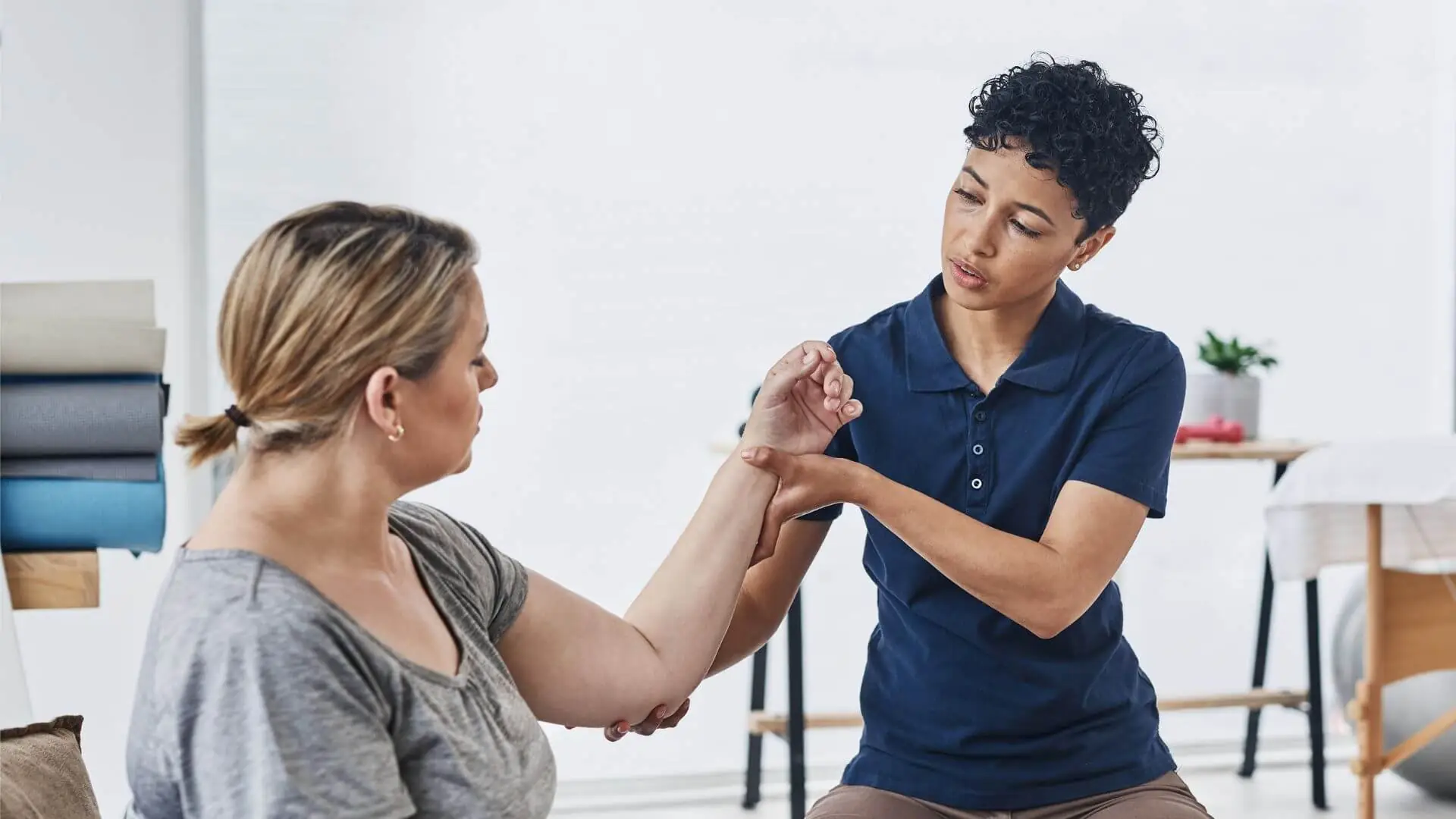young female PT with female patient holding arm young female PT with female patient holding arm